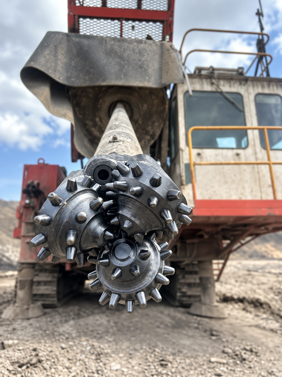 Ilustrasi tricone drill bit di depan rotary drill rig pada area tambang